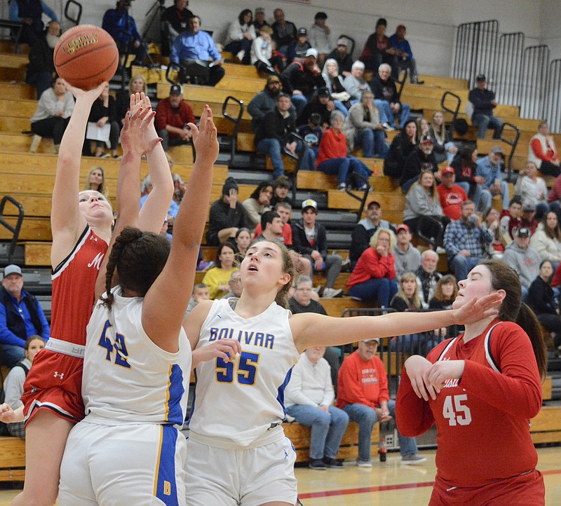 Bennett Horne/McDonald County Press Lady Mustang Carlee Cooper (left) shoots over two Bolivar defenders while teammate Roslynn Huston is kept from moving in for a rebound in McDonald County's 61-33 loss in the opening round of the Class 5 District 7 Basketball Tournament at Webb City on Thursday, March 2.