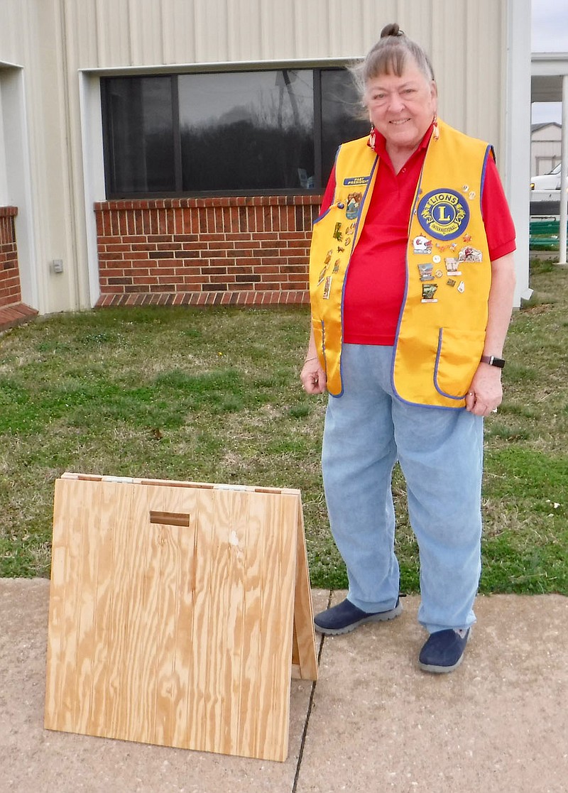 Susan Holland/Westside Eagle Observer
Linda Damron, treasurer of the Gravette Lions Club, poses with one of the club's new sandwich board signs following the group's regular meeting Tuesday, March 7, at the Billy V. Hall Senior Activity Center. Jake Damron, a friend of the club, donated time, materials and labor to make two of the signs. They will be used to advertise upcoming events.