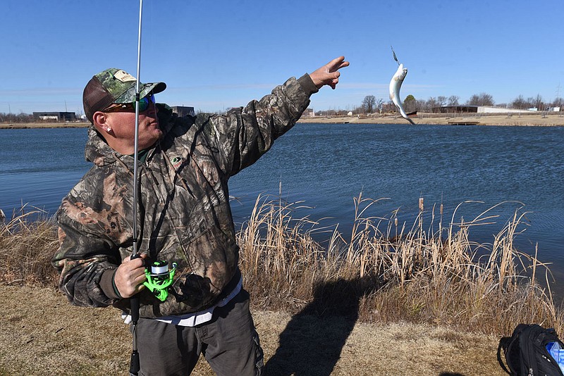 Josh Williams of Bentonville lands his 23rd rainbow trout during a morning of fishing at Lake Bentonville. The daily limit is five but Williams was releasing his fish. All were caught with a small spoon. The lake is one of several across the state stocked with trout by the Arkansas Game and Fish Commission for winter fishing.
(NWA Democrat-Gazette/Flip Putthoff)