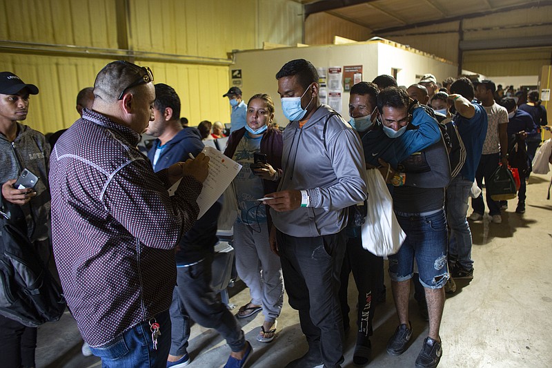 FILE - People line up for a commercial bus that will take them to the San Antonio airport at a warehouse run by the Mission: Border Hope nonprofit group run by the United Methodist Church in Eagle Pass, Texas, on May 23, 2022. The Border Patrol releases up to 1,000 migrants daily at Mission: Border Hope. A federal judge on Wednesday, March 8, 2023, ordered the Biden administration to end expedited releases of migrants who enter the United States illegally from Mexico, potentially straining already stretched holding facilities. (AP Photo/Dario Lopez-Mills, File)