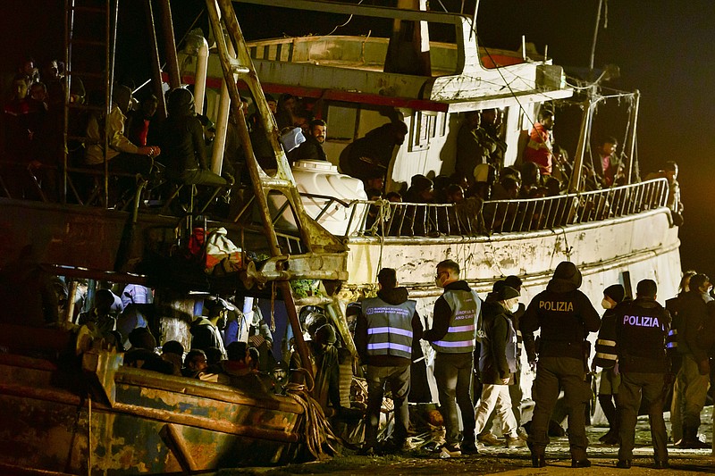 Police check a fishing boat with some 500 migrants in the southern Italian port of Crotone, early Saturday, March 11, 2023. The Italian coast guard was responding to three smugglers boats carrying more than 1,300 migrants “in danger” off Italy’s southern coast, officials said Friday. Three small coast guard boats were rescuing a boat with 500 migrants about 700 miles off the Calabria region, which forms the toe of the Italian boot. (AP Photo/Valeria Ferraro)