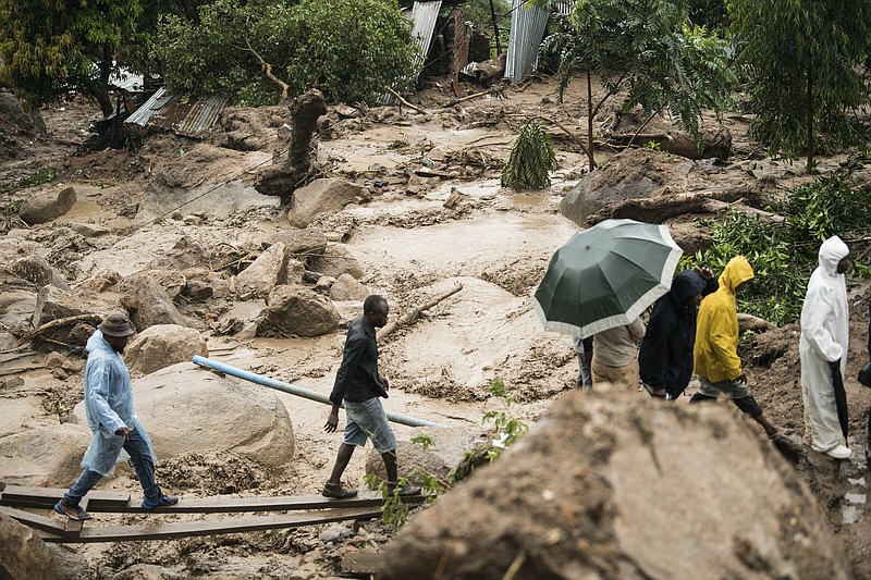 People cross a raging river in Blantyre, Malawi, Monday, March 13, 2023. An unrelenting Cyclone Freddy that is currently battering southern Africa has killed at least 56 people in Malawi and Mozambique since it struck the continent for a second time on Saturday night, authorities in both countries have confirmed. (AP Photo/Thoko Chikondi)