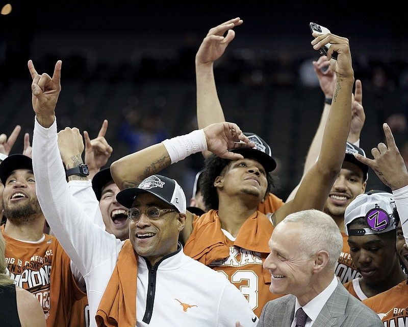 Interim Texas head coach Rodney Terry, front left, celebrates with Big 12 commissioner Brett Yormark, right, after his team won the NCAA college basketball championship game in the Big 12 Conference tournament Saturday, March 11, 2023, in Kansas City, Mo. Texas won 75-56. (AP Photo/Charlie Riedel)