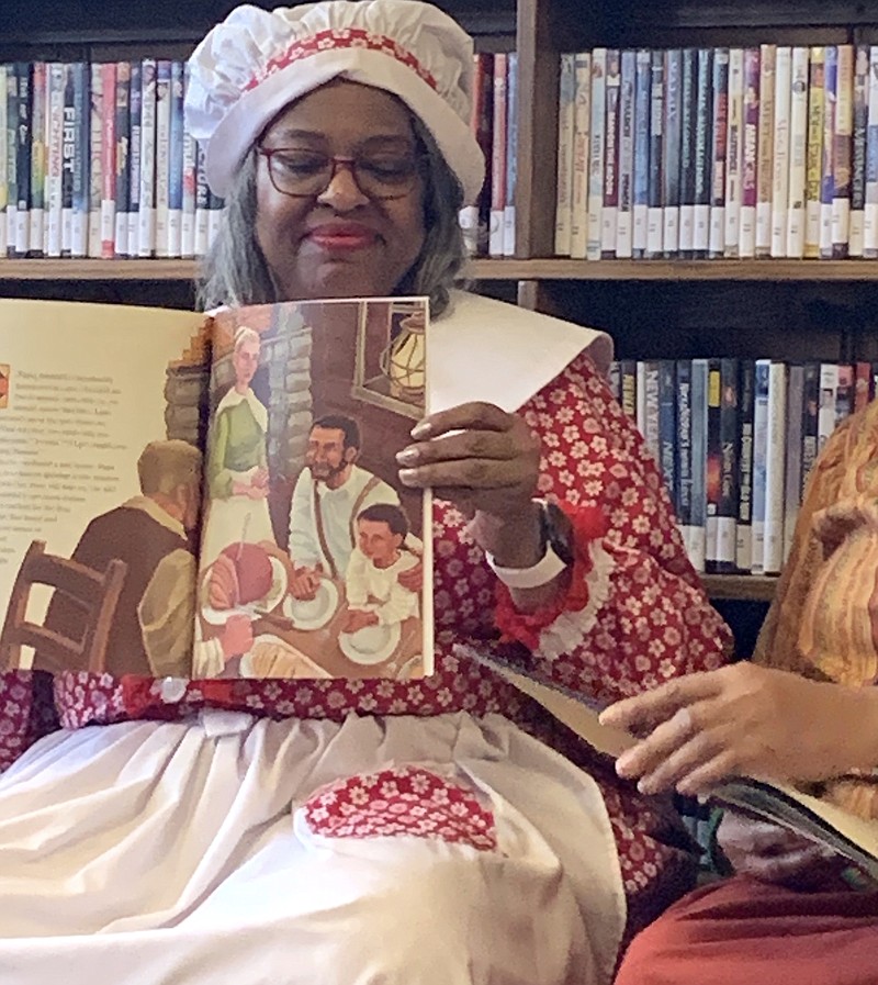 Laura Smith of the Pleasant Hill Quilting Club holds the children’s book “The Patchwork Path” for second-graders at the Linden Public Library. The book is taken from the adult version “Hidden in Plain View,” which tells the story of the secret code quilts of the underground railroad. (Submitted photo)