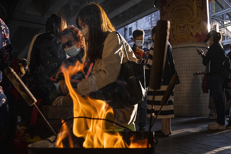 Customers watch a &quot;villain hitting&quot; ceremony on the day of &quot;ging zat,&quot; as pronounced in Cantonese, which on the Chinese lunar calendar literally means &quot;awakening of insects,&quot; under the Canal Road Flyover in Hong Kong on Monday, March 6, 2023. (AP Photo/Louise Delmotte)