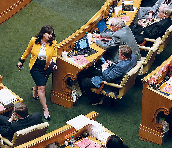 Rep. Mindy McAlindon (center), R-Centerton, returns to her seat Tuesday after listening to debate about SB66 on the floor of the House of Representatives at the Arkansas state Capitol in Little Rock. (Arkansas Democrat-Gazette/Colin Murphey)