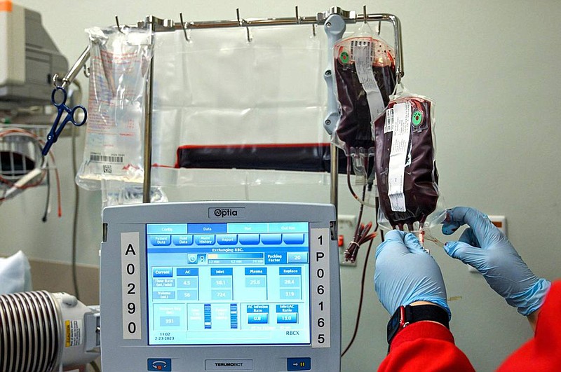 A worker from the Community Blood Center hangs a bag of blood during a transfusion for Kevin Wake at the Sickle Cell Center at University Health. (Tammy Ljungblad/The Kansas City Star/TNS)