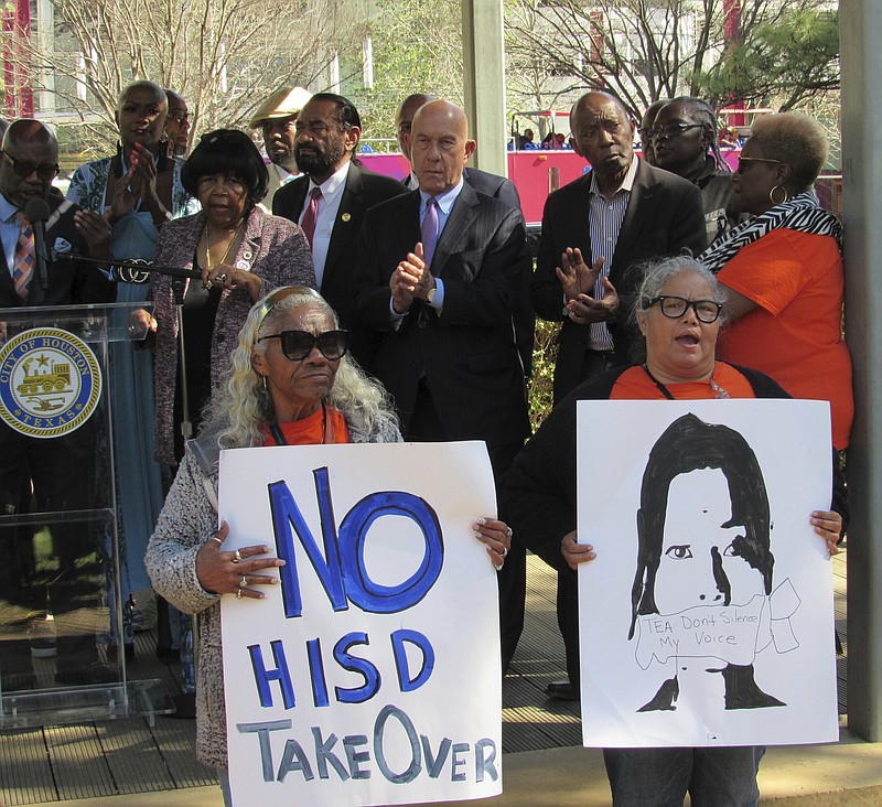 People hold up signs at a news conference Friday, March 3, 2023, in Houston while protesting the proposed takeover of the city's school district by the Texas Education Agency. Texas officials on Wednesday, March 15, announced a state takeover of Houston's nearly 200,000-student public school district, the eighth-largest in the country, acting on years of threats and angering Democrats who assailed the move as political. (AP Photo/Juan A. Lozano)