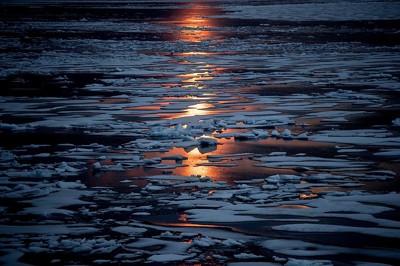 The midnight sun shines across sea ice along the Northwest Passage on July 23, 2017, in the Canadian Arctic Archipelago. A new study Wednesday, March 15, 2023, says the thickness of sea ice dropped sharply in two sudden events about 15 years ago. (AP Photo/David Goldman, File)