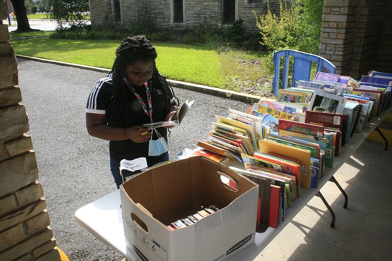 A student peruses the selections at a Friends of Barton Library book sale in this News-Times file photo. The Friends' spring book sale is scheduled to start next week.