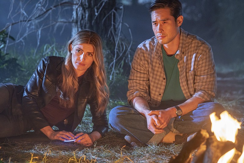 Caitlin Bassett (left) and Raymond Lee talk by a campfire in a scene from NBC’s “Quantum Leap.” Bassett is an Army veteran and former law student who ultimately chose acting as her career, only to wind up on a hit show. (Ron Batzdorff/NBC via AP)