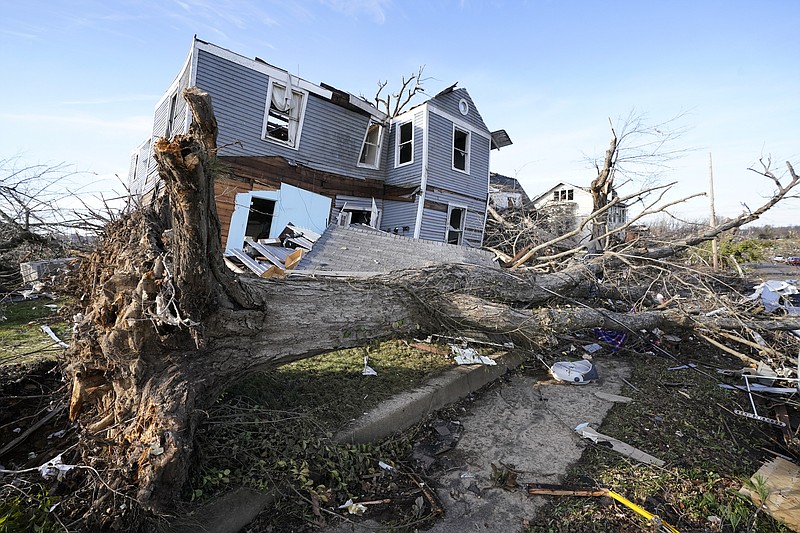 An overturned tree sits in front of a tornado-damaged home Dec. 11, 2021, in Mayfield, Ky. Stories circulating online incorrectly claim climate, weather or meteorological events that would be classified as “extreme” have declined in severity over the last 20 or 30 years. (File Photo/AP/Mark Humphrey)