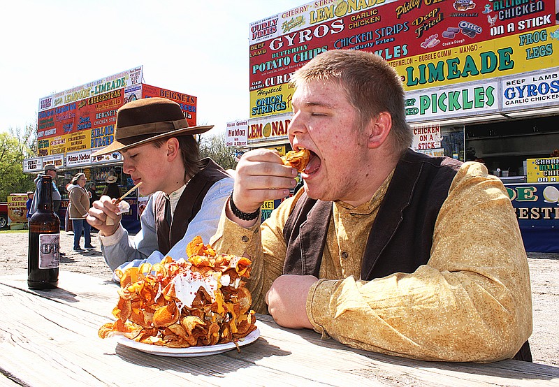 William Lanthrip, of Monticello, Ark., takes a bite from a plate of butterfly chips as Job Rodgers, of Monticello, finishes a corn dog on the first day of the Jonquil Festival on Friday, March 17, 2023, at Historic Washington State Park in Washington, Ark. Lanthrip and Rodgers are park volunteers. The festival continues through Sunday, March 19. (Staff photo by Stevon Gamble)