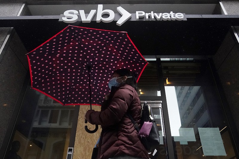 A pedestrian carries an umbrella while walking past a Silicon Valley Bank Private branch in San Francisco, Tuesday, March 14, 2023. (AP Photo/Jeff Chiu)