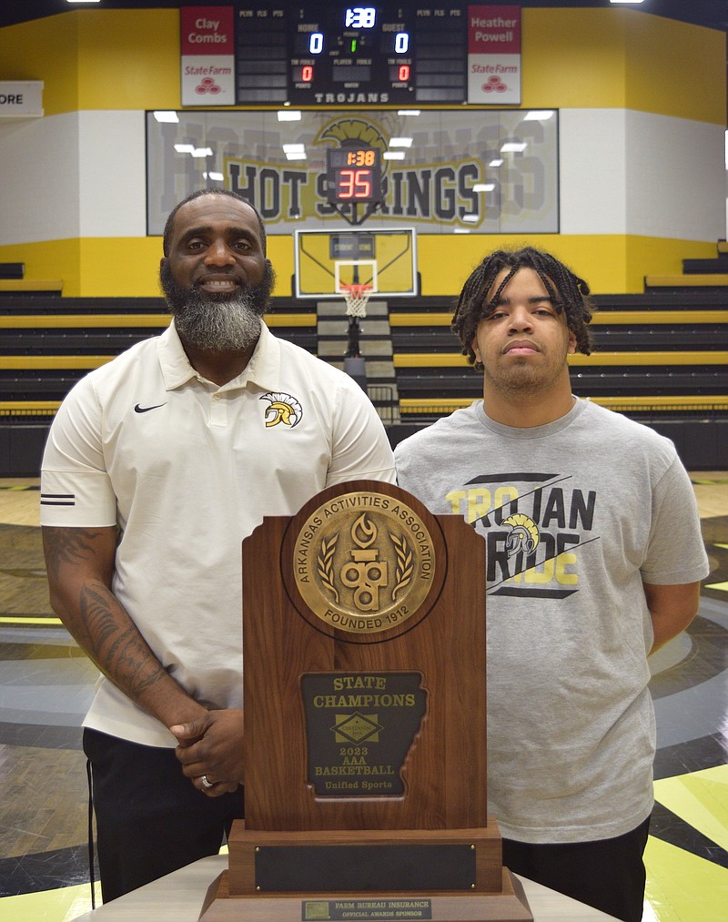 Hot Springs unified basketball head coach Larry McDaniel and senior athlete Roy Byers stand with the state championship trophy Thursday at Trojan Arena. - Photo by Donald Cross of The Sentinel Record