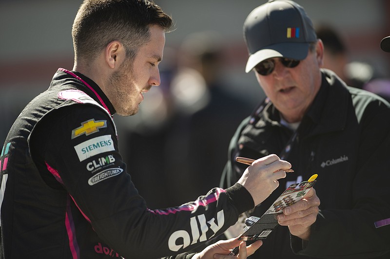 Driver Alex Bowman, left, signs autograph before qualifying for the NASCAR Cup Series auto race at Atlanta Motor Speedway on Saturday, March 18, 2023, in Hampton, Ga. (AP Photo/Hakim Wright Sr.)