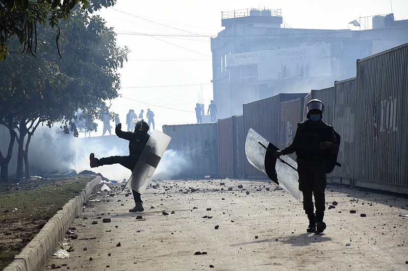 Police officer throw stones towards the supporters of former Prime Minister Imran Khan during clashes, at outside the a court, in Islamabad, Pakistan, March 18, 2023. Pakistani police stormed former Prime Minister Khan's residence in the eastern city of Lahore on Saturday and arrested 61 people amid tear gas and clashes between Khan's supporters and police, officials said. (AP Photo/W.K. Yousafzai)