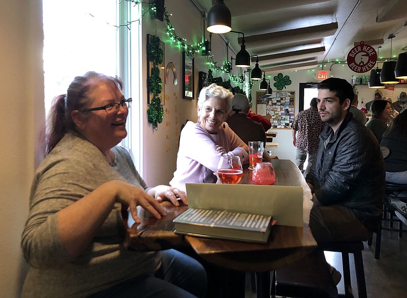 DeLani Bartlette (left) speaks to patrons Wednesday, March 15, 2023, at Crisis Brewing in Fayetteville about starting a local Strong Towns group as Deborah Capp and David Halperin look on. Strong Towns is a national organization that encourages residents to help solve planning issues in their communities. (NWA Democrat-Gazette/Stacy Ryburn)