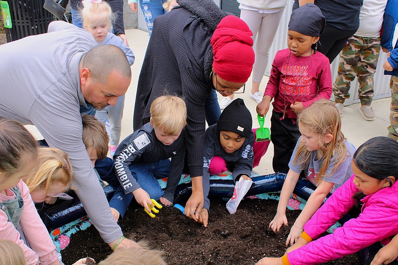 Sabrena Mays, standing center, helps her child Lesedii Zoneema, 6, dig for fossils. (Caitlan Butler/News-Times)