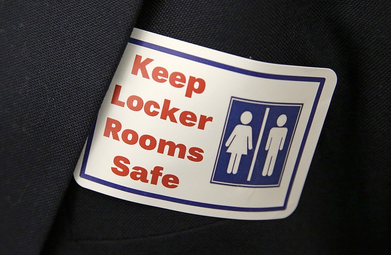 FILE - A sticker that reads, "Keep Locker Rooms Safe," is worn by a person supporting a bill that would eliminate Washington's rule allowing transgender people use gender-segregated bathrooms and locker rooms in public buildings consistent with their gender identity, on Jan. 27, 2016, at the Capitol in Olympia, Wash. On Tuesday, March 21, 2023, Arkansas Gov. Sarah Huckabee Sanders signed a law prohibiting transgender people at public schools from using the restroom that matches their gender identity. Arkansas' law applies to multi-person restrooms and locker rooms at public schools and charter schools serving prekindergarten through 12th grade. (AP Photo/Ted S. Warren, File)