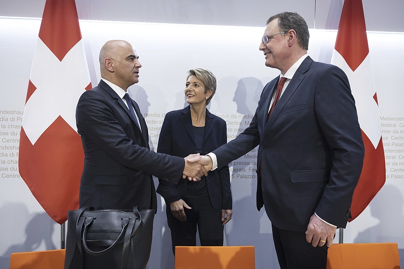 Swiss Federal President Alain Berset, left, and Thomas J. Jordan, Chairman Swiss National Bank, right, shake hands beside Swiss Finance Minister Karin Keller-Sutter, at the end of a press conference in Bern, Switzerland, Sunday March 19, 2023.  Banking giant UBS is acquiring its smaller rival Credit Suisse in an effort to avoid further market-shaking turmoil in global banking, Swiss President Alain Berset announced on Sunday. (Peter Klaunzer/Keystone via AP)