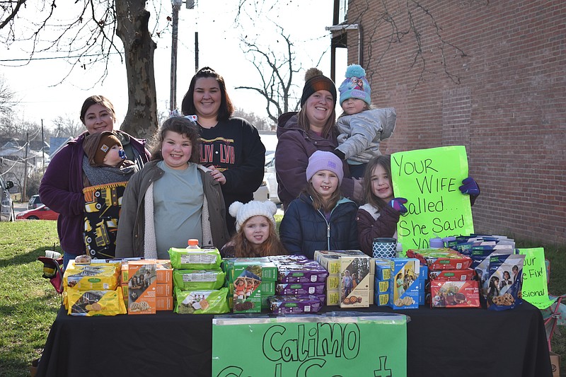 Democrat photo/Garrett Fuller — Children and adults with Girl Scouts Troop 72077 smile for a photo Saturday (March 25, 2023,) during cookie sales near Grind Coffee & Bistro. Children pictured in front, from left, are: Brooklynn Taylor, Oakley Wadley, Ashtyn Wadley and Addilynn Taylor. In rear, from left, are: Peydon Wadley, Tiffany Taylor, Mary Bleich and Harlee Wadley.