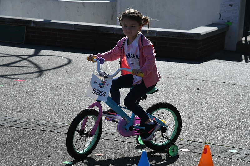 A girl rides around the cones laid out at the Hot Springs Transportation Depot on a borrowed bike at Tikes, Trikes and Trails. - Photo by Lance Brownfield of The Sentinel-Record.