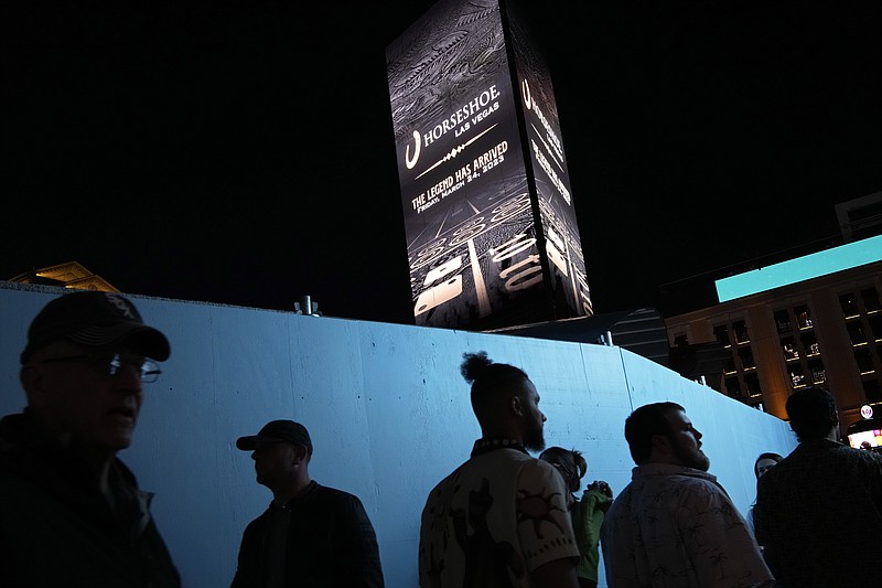 People walk by a sign for the Horseshoe Las Vegas along the Strip, late Friday, March 24, 2023, in Las Vegas. Caesars Entertainment marked the rebranding of Bally's Las Vegas as the Horseshoe Las Vegas hotel & casino. (AP Photo/John Locher)