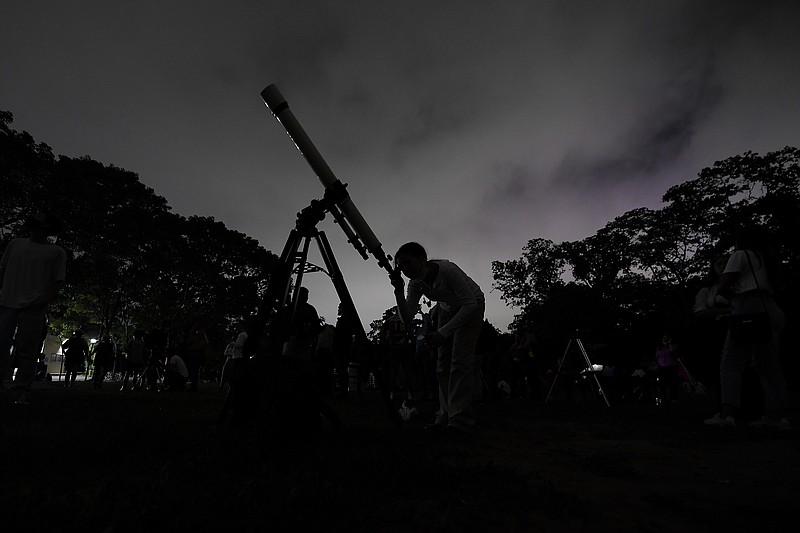 A girl looks at the moon through a telescope Sunday, May 15, 2022, in Caracas, Venezuela. The best day to spot five planets, Mercury, Jupiter, Venus, Uranus and Mars, lined up in the night sky is Tuesday, March 28, 2023, right after sunset. The five-planet array will be visible from anywhere on Earth, as long as you have clear skies. (AP Photo/Matias Delacroix)