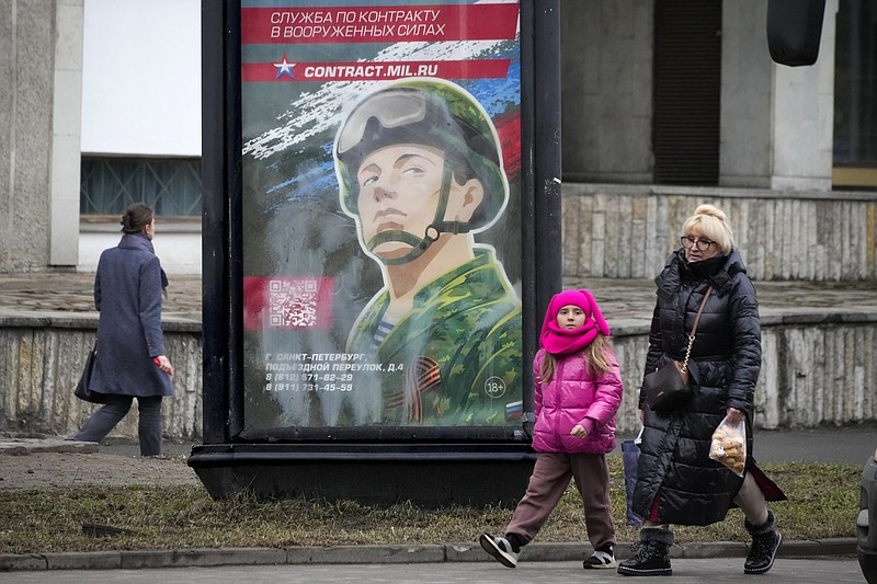 People walk past an army recruiting billboard with the words "Military service under contract in the armed forces" in St. Petersburg, Russia, Friday, March 24, 2023.  A campaign to replenish Russian troops in Ukraine with more soldiers appears to be underway again, with makeshift recruitment centers popping up in cities and towns, and state institutions posting ads promising cash bonuses and benefits to entice men to sign contracts enabling them to be sent into the battlefield. (AP Photo)