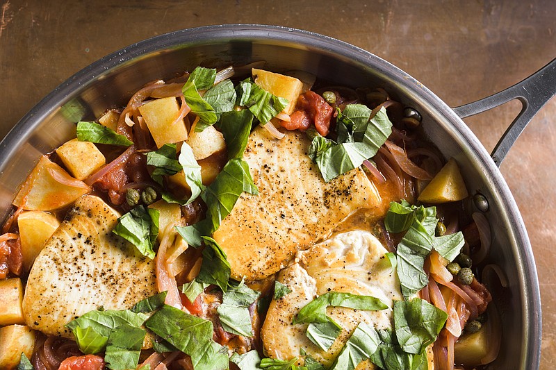 This image released by Milk Street shows a recipe for swordfish with potatoes, tomatoes and capers. (Milk Street via AP)