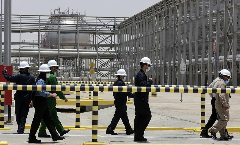 FILE - Saudi Aramco engineers escort reporters on a tour of the Hawiyah Natural Gas Liquids Recovery Plant, which is designed to process 4.0 billion standard cubic feet per day of sweet gas, a natural gas that does not contain significant amounts of hydrogen sulfide, in Hawiyah, in the Eastern Province of Saudi Arabia, on June 28, 2021. Saudi Arabia's state-owned oil giant Aramco will invest billions of dollars in China's downstream petrochemicals industry, including the construction of a new refinery, the company said in deals announced Sunday and Monday.(AP Photo/Amr Nabil, File)