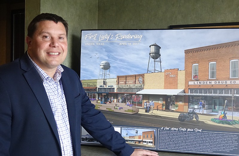 Linden City Manager Lee Elliott has recently been appointed to the Texas Municipal League’s Small Cities Advisory Council. He is shown before a rendering by the Texas Main Street program of how Linden might look with its downtown area developed as a historic site. (Photo by Neil Abeles)