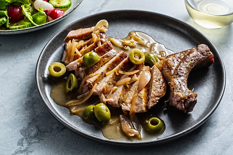 A pork chop with onions and olives - a photo of a dirty martini pork chop (Washington Post)