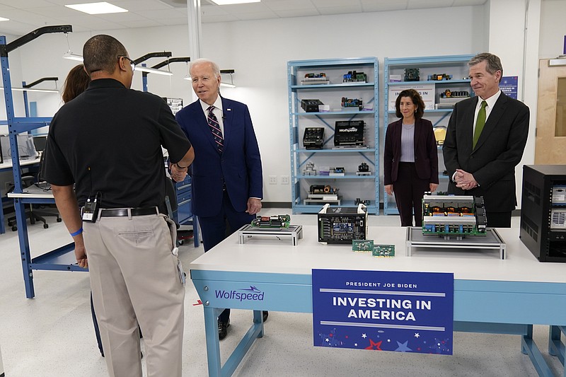 President Joe Biden greets employees as he tours semiconductor manufacturer Wolfspeed Inc., in Durham, N.C., Tuesday, March 28, 2023, as North Carolina Gov. Roy Cooper, right, and Commerce Secretary Gina Raimondo watch. (AP Photo/Carolyn Kaster)