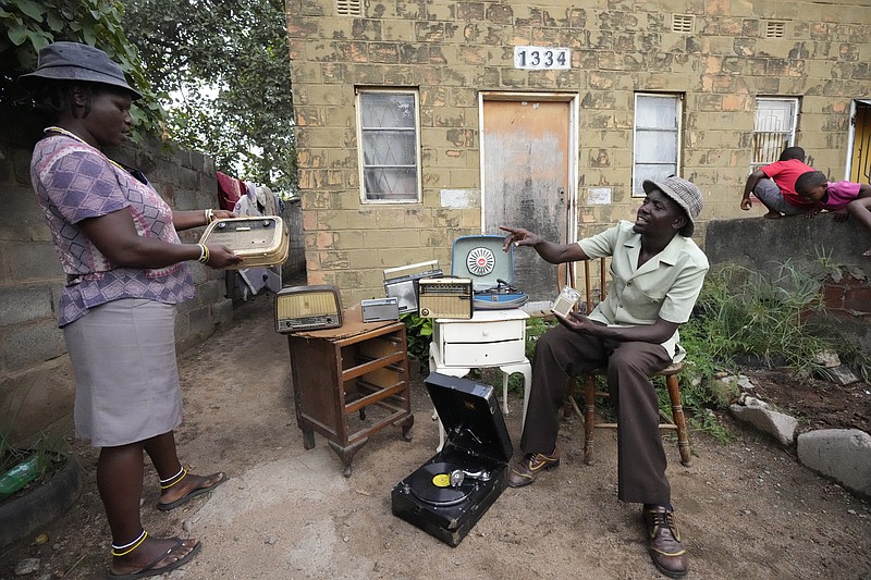 Ngwiza Khumbulani Moyo (right), a collector, displays some of his old radio sets Feb. 15 outside his home in Bulawayo, Zimbabwe. (AP/Tsvangirayi Mukwazhi)