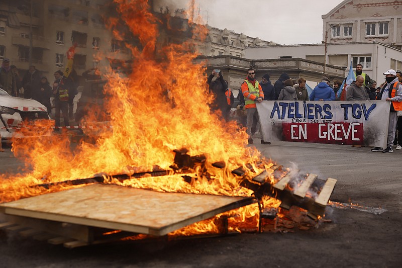 Striking railway workers demonstrate near burning palettes at the Gare de Lyon train station, Tuesday, March 28, 2023 in Paris. A new round of strikes and demonstrations is planned against the unpopular pension reforms that, most notably, push the legal retirement age from 62 to 64. (AP Photo/Thomas Padilla)