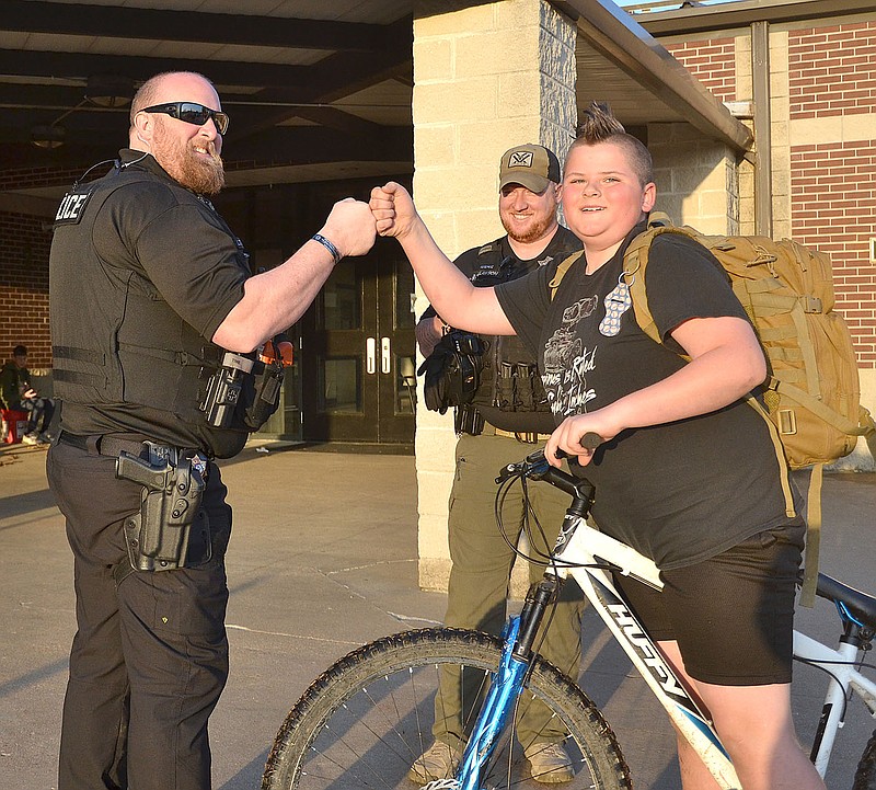Annette Beard/Pea Ridge TIMES
Pea Ridge Police Lt. Rich Fordham and Officer Justin Lawson greet students outside Pea Ridge Middle School Monday morning after spending the night searching the buildings for a bomb. Fifth-grader Braden Yordy greet Lt. Fordham as he pulled up at the school on his bicycle.