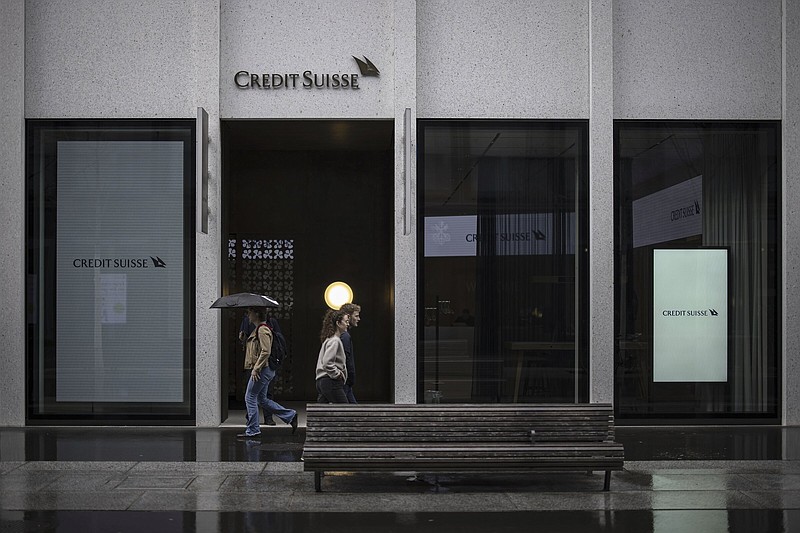 People walk past a logo of the Swiss bank Credit Suisse in Zurich, Switzerland, Friday, March 24, 2023. (Michael Buholzer/Keystone via AP)