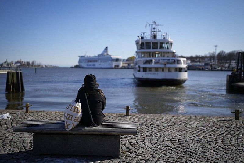 A woman sits on a embarkment in Helsinki, Finland, Monday, April 3, 2023. NATO Secretary-General Jens Stoltenberg said Monday Finland will become the 31st member of the world's biggest military alliance on Tuesday, prompting a warning from Russia that it would bolster its defenses near their joint border if NATO deploys any troops in its new member. (AP Photo/Sergei Grits)
