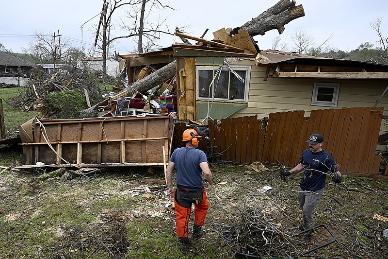 Landon Milhorn, left, and Matthew Driggers, both members of the US Coast Guard, carry pieces of wood cut from a fallen tree as they help with disaster relief in Sherwood on Monday, April 3, 2023. More photos at arkansasonline.com/44tornado/

(Arkansas Democrat-Gazette/Stephen Swofford)