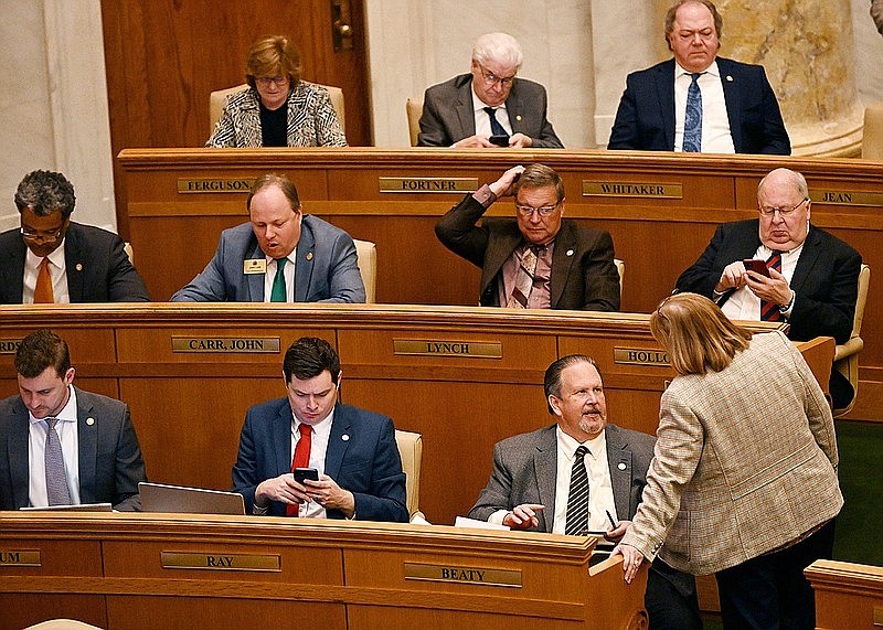 Rep. Howard Beaty, R-Crossett talks with Rep. Frances Cavenaugh (bottom right), R-Walnut Ridge, during the House session Wednesday. Beatys House Bill 1045 to gradually phase out the “throwback rule” on business income over a seven-year period gained the backing of the Senate Revenue and Taxation Committee. (Arkansas Democrat-Gazette/Staci Vandagriff)