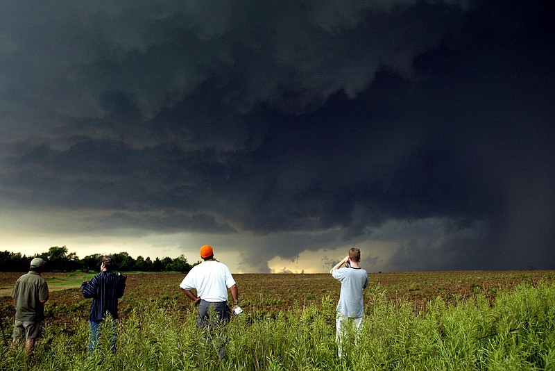 (NYT40) NORTH CENTRAL KANSAS -- June 6, 2004 -- TORNADO-TOURISTS -- Members of Storm Chasing Adventure Tours look for signs of tornadoes in a field in north central Kansas on June 2, 2004. This is high season in Tornado Alley, the swath of the Great Plains from Texas to North Dakota where heat, moisture and shearing winds create just the right brew for the whirling funnel storms that are one of natures most terrifying spectacles. But growing ranks of aficionados now come barreling in, the vanguard of a booming mini-industry of storm-chasers whose passion translates into tourism dollars gratefully harvested by small-town motels and restaurants. Sometimes, too, they help sound the alarm and assist victims.  (Ting-Li Wang/The New York Times)