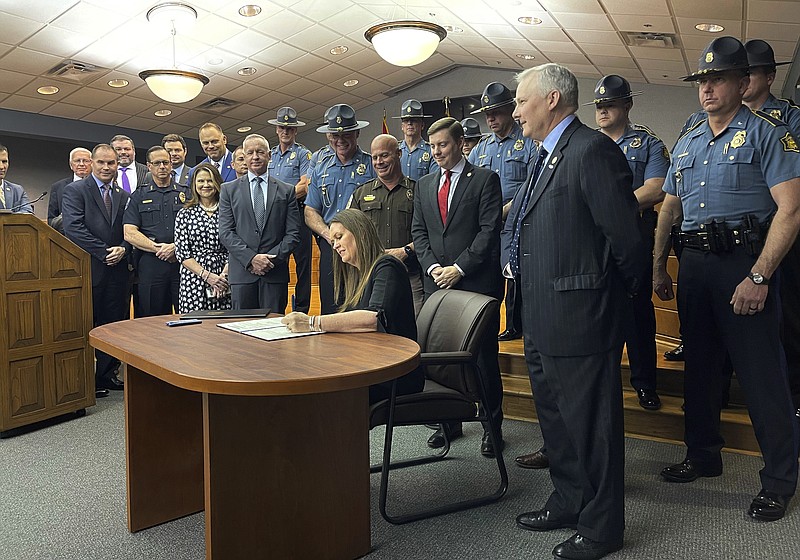 Arkansas Gov. Sarah Huckabee Sanders signs legislation, Tuesday, April 11, 2023, at the Arkansas State Police headquarters in Little Rock, Ark., that will overhaul the state's sentencing laws. The new law will eliminate parole eligibility for certain violent offenses. (AP Photo/Andrew DeMillo)
