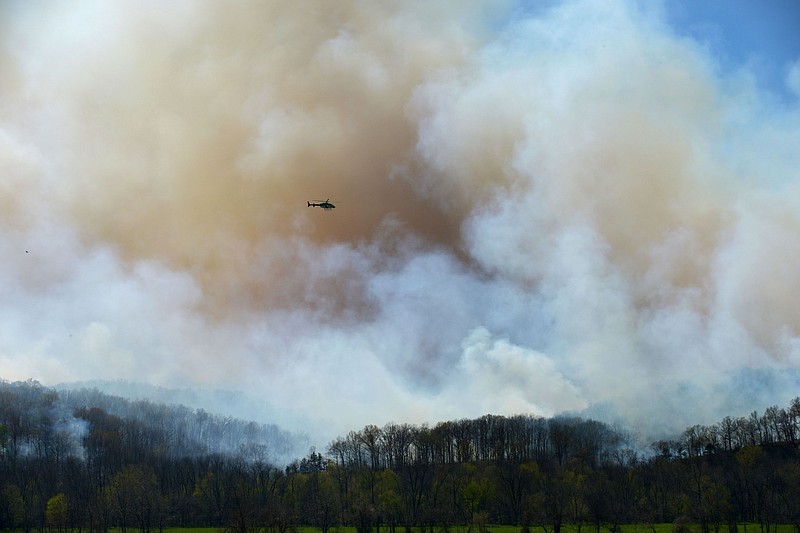A helicopter circles a plume of smoke on Monday April 4, 2016 rising from the Ozark National Forest west of Tontitown as seen from Robinson Road. (NWA Democrat-Gazette/BEN GOFF)