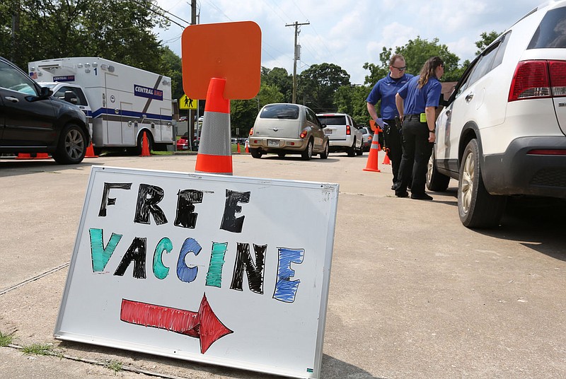 Melissa Snider (right), paramedic with Central EMS, and Levi Turner, emergency medical technician, on July 20, 2021, prepare to give a driver a covid-19 vaccination shot during a weekly St. James Missionary Baptist Church Food Pantry at the Squire Jahagen Arts and Outreach Center located at 115 S. Willow Avenue in Fayetteville. The city's Board of Health on Wednesday cited concerns over disproportionate impacts on low-income residents associated with the end of the federal public health emergency on May 11. 
(File photo/NWA Democrat-Gazette/David Gottschalk)