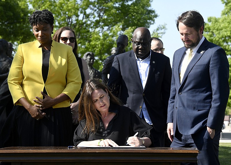Gov. Sarah Huckabee Sanders signs a bill to allow a specialty license plate in honor of Central High School during a signing event in front of the Little Rock Nine memorial Tuesday, April 18, 2023, at the state Capitol in Little Rock. (Arkansas Democrat-Gazette/Stephen Swofford)