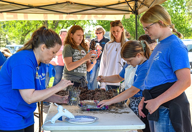 Julie Smith/News Tribune
Using a hot glue gun, Sandy Buescher adheses sticks and moss into a a two-liter soda jug that ws cut in two as she makes a bug hotel for Katie Kloeppel, at right, during Friday's Earth Day MO activities at the Capitol. Kloeppel attends Visitation Inter-Parish School in Vienna and made the trip with classmates, teachers and parents to learn about and celebrate the natural environment. Buescher works for Department of Natural Resources Water Protection Program and was at one of nearly two dozen booths that were set up to show students about Missouri's environmental landscape.