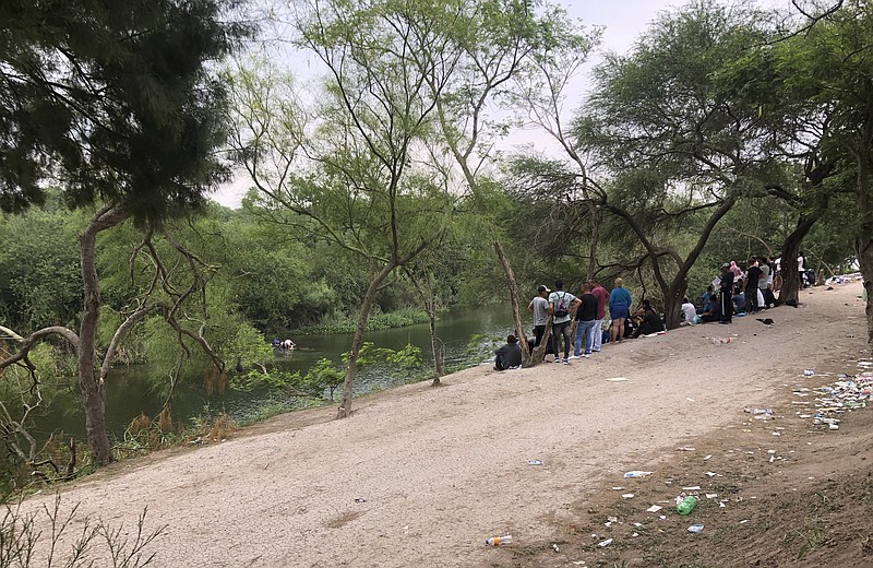 People standing on the bank of the Rio Grande in Matamoros, Mexico, watch others cross the river into the United States, Friday, April 21, 2023. About two dozen makeshift tents in the area were set ablaze and destroyed at a migrant camp across the border from Texas this week, witnesses said. (AP Photo/Valerie Gonzalez)