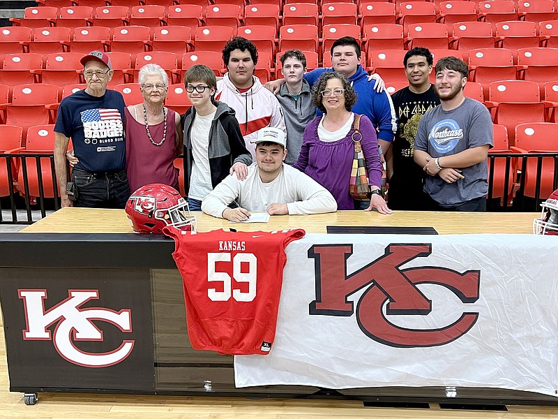 Graham Thomas/Herald-Leader
Kansas senior football player Ethan Cooke (seated) signed a letter of intent to play football at Kansas Wesleyan on Wednesday, April 19, in the Kansas Event Center. Pictured with Cooke are (middle from left) grandparents James and Georgene Chamberlain, brother Issiah Sexton, mother Charlotte Cooke and friends (back) Yona Shay, Isaiah Church, Jacob Drywater, Sylvester Slammons and Treygan Rodriguez.